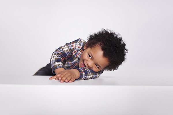 Happy excited little African American boy in casual clothes is posing isolated on white background